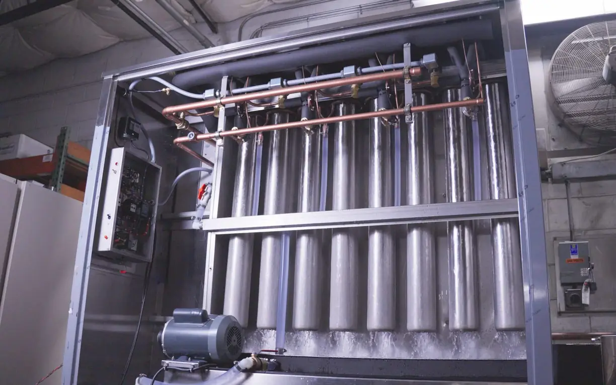 Commercial industrial ice maker machine Arctic-Temp® ice machine with its panel open, showing the stainless steel evaporator tubes and copper lines