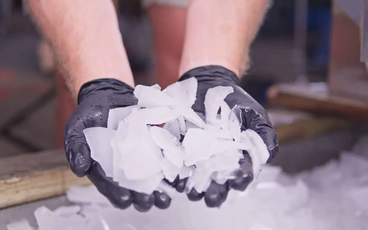 cracked industrial ice Gloved hands holding a handful of hard cracked ice pieces over a pile of ice