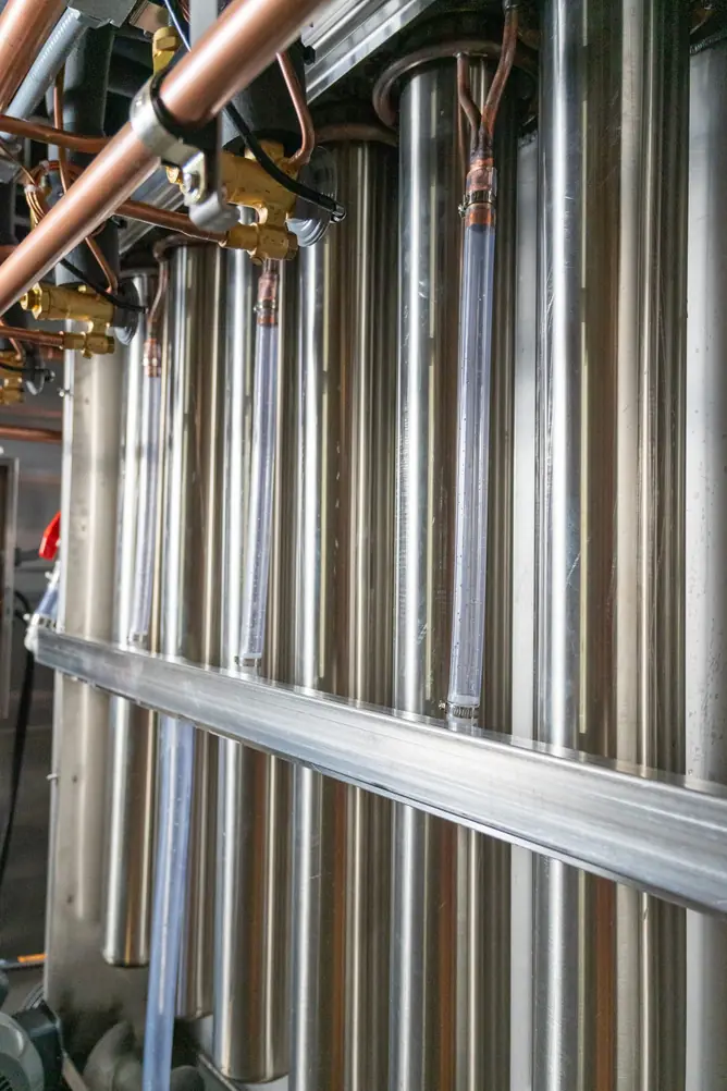 Close-up of stainless steel evaporator tubes with copper fittings and clear water tubes inside an Arctic-Temp® ice machine