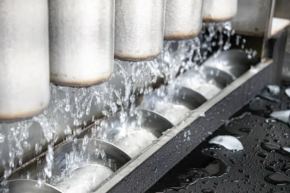 Water pouring off ice-covered evaporator tubes onto the cutter screw inside an ice machine